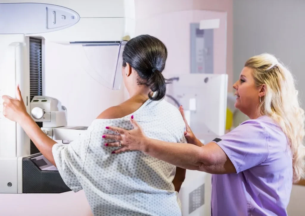 a nurse assists a woman with her mammogram